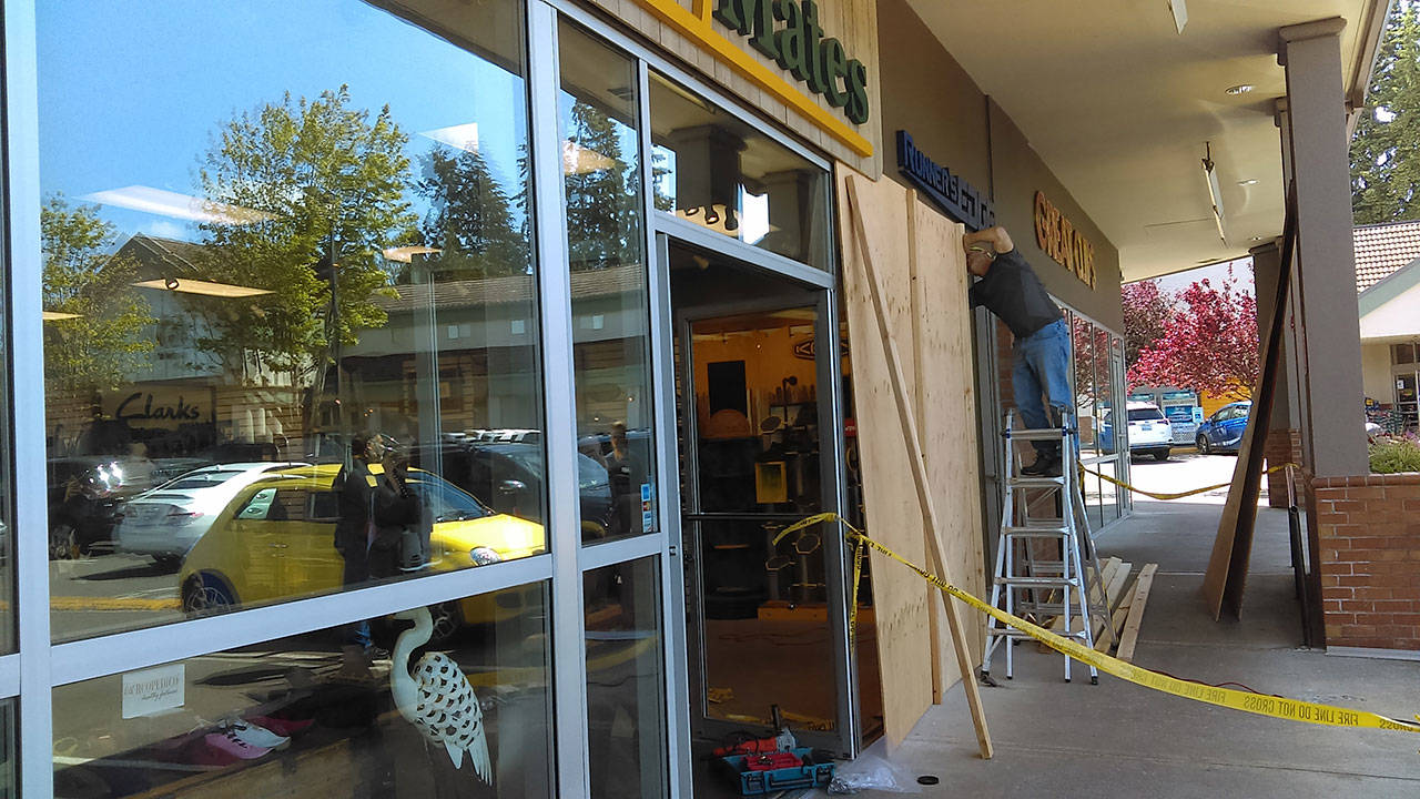 Luciano Marano | Bainbridge Island Review - Makeshift, temporary repairs are made after the front window of Sole Mates Shoes, in the Island Village Shopping Center, was smashed by a car, which drove over the curb and sidewalk and into the store on May 30.
