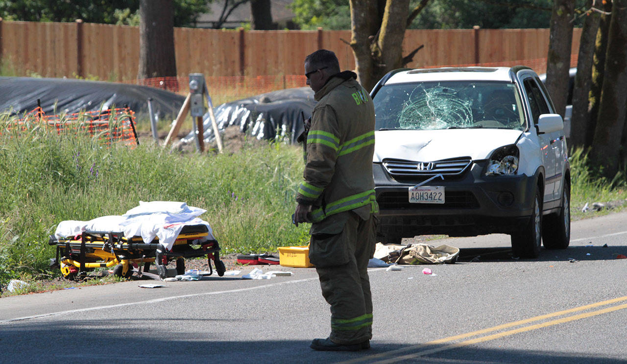 A Bainbridge Island firefighter stands at the scene of a collision where two joggers were struck by a car on Father’s Day.                                (Brian Kelly | Bainbridge Island Review)