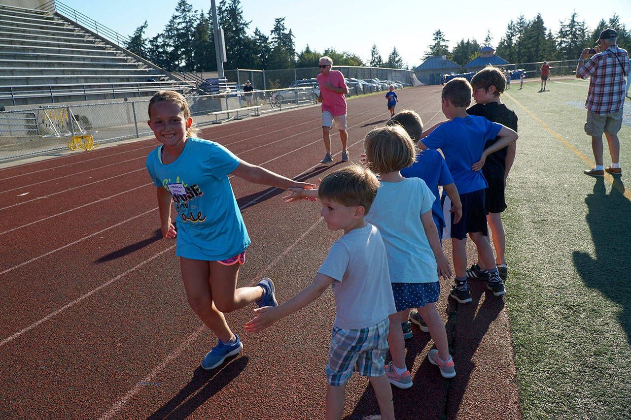 Luciano Marano | Bainbridge Island Review - Campbell Johnson, 9, gets a series of high fives as she sprits through the last leg of the Jogger’s Mile event at Monday’s community track meet.