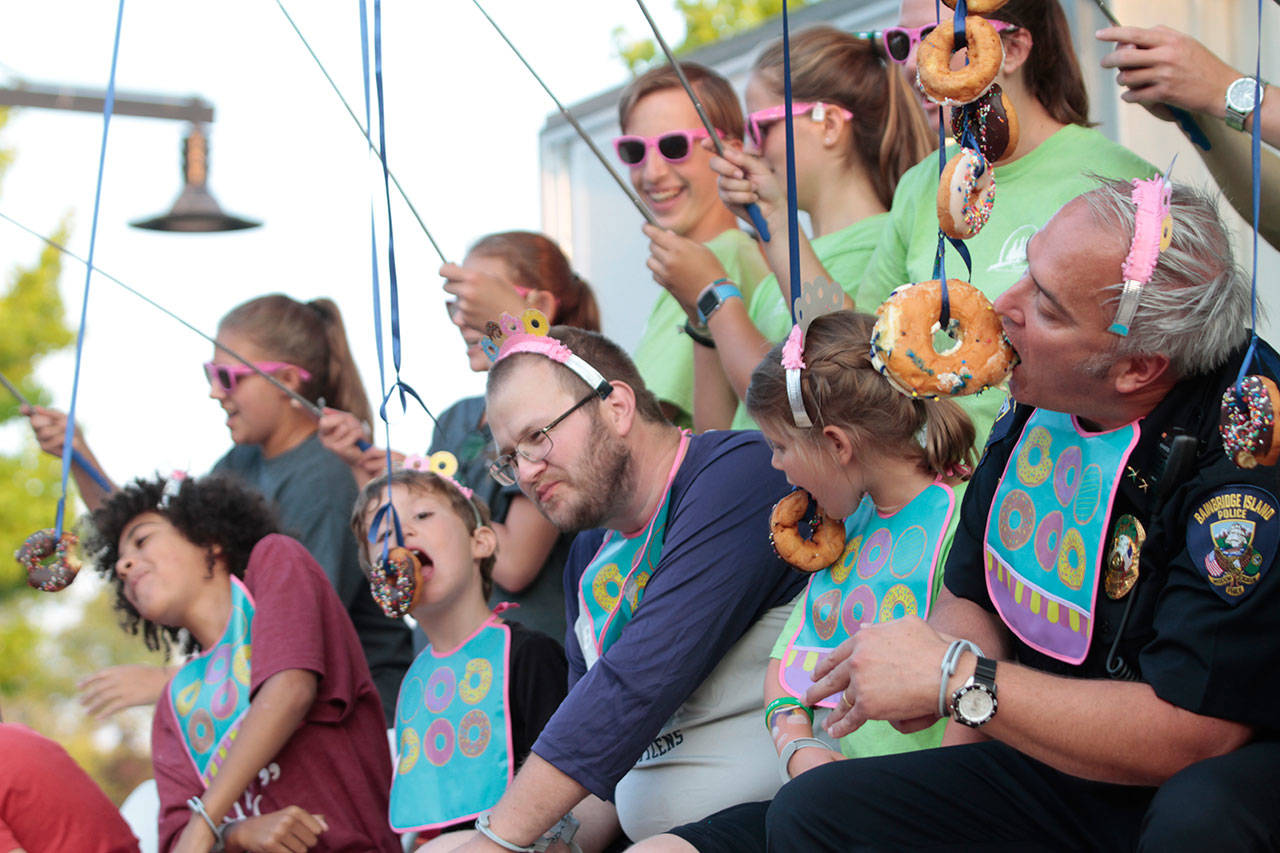 Islanders compete against Police Chief Matthew Hamner (far right) in the doughnut-eating contest at last years National Night Out. (Luciano Marano | Bainbridge Island Review)