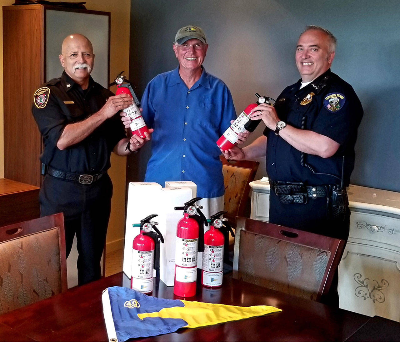 Eagle Harbor Yacht Club Vice Commodore Terry Kerby (center) presents fire extinguishers to Fire Chief Hank Teran and Police Chief Matt Hamner. (Photo courtesy of the Eagle Harbor Yacht Club)