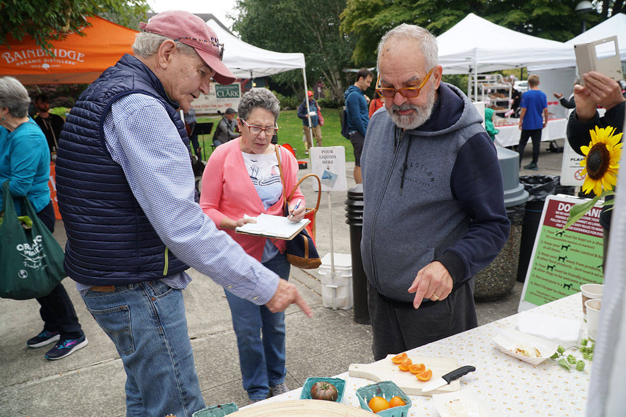Luciano Marano | Bainbridge Island Review - Anthony and Christine Farrell and Bob Ross, the judges of this year’s farmers market Tomato Taste Off, discuss an entrant Saturday, Aug. 25.