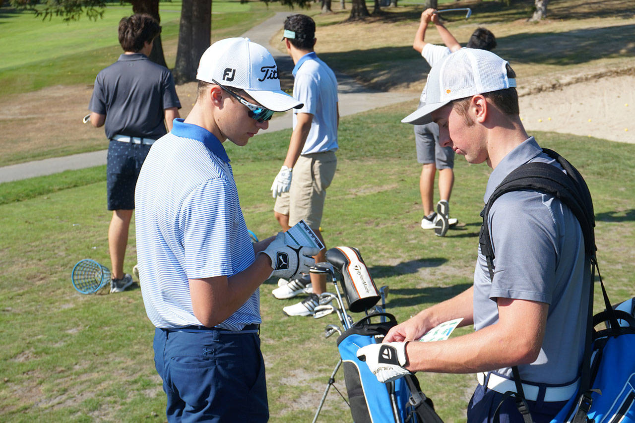 Luciano Marano | Bainbridge Island Review - Members of the Bainbridge High School boys varsity golf team exchange score cards before a practice round.