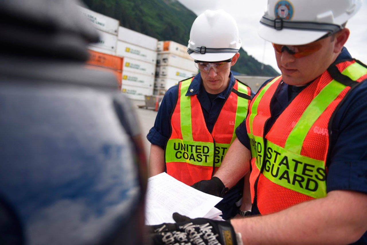 Petty Officer 3rd Class Lewis Beck and Petty Officer 2nd Class Chris Houvener, both marine science technicians at Coast Guard Sector Juneau, look through federal regulations during a container inspection in Juneau, Alaska, June 19, 2015. Coast Guard inspectors follow rigid, standardized regulations to ensure maritime operators across the country are held to the same rules. (U.S. Coast Guard photo by Petty Officer 2nd Class Grant DeVuyst)