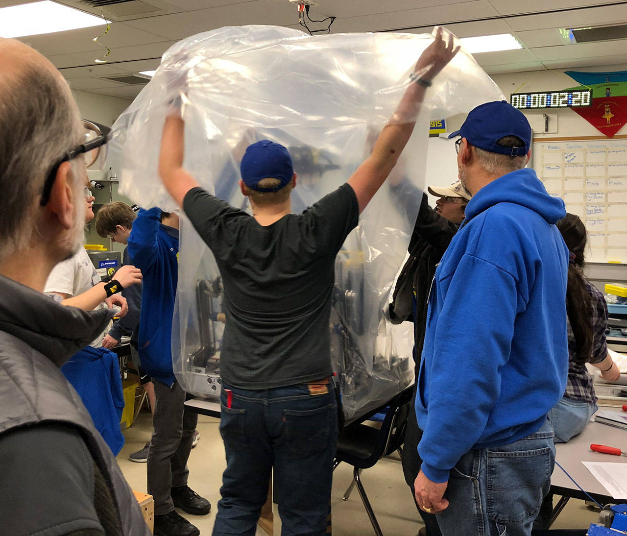 Bainbridge High students put their new robot, CHAOS, under a protective bag. CHAOS will meet the island community at an open house Wednesday, March 13 at BHS, where members of the 4915 Spartronics, the school’s robotics team, will show off their latest creation. (Photo courtesy of 4915 Spartronics)
