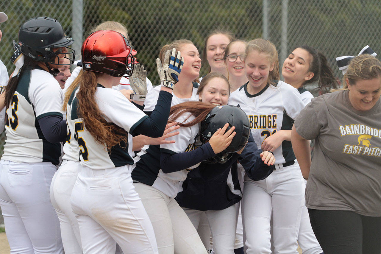 Ruby Raymundo is mobbed at home plate after she hit a two-run homer against Seattle Prep in last week’s fastpitch softball matchup. (Brian Kelly | Bainbridge Island Review)