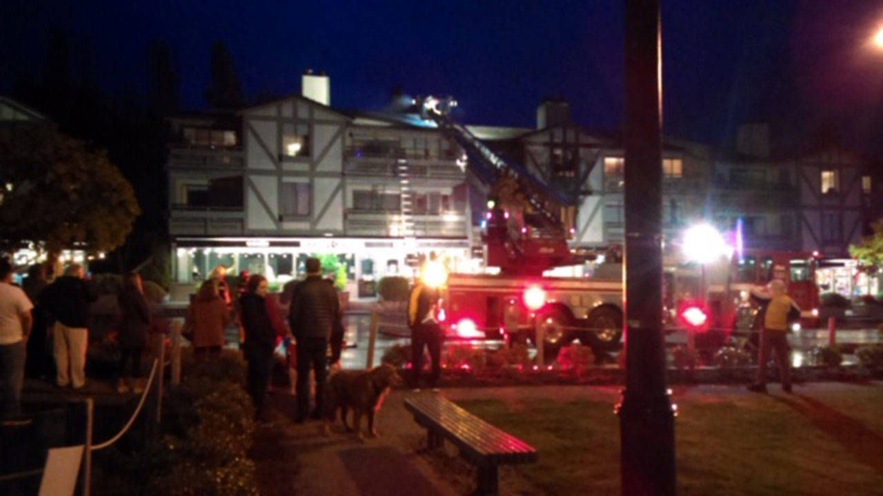 Onlookers gather as emergency crews respond to a fire at the Winslow Green complex in downtown Winslow Thursday night. (Luciano Marano | Bainbridge Island Review)