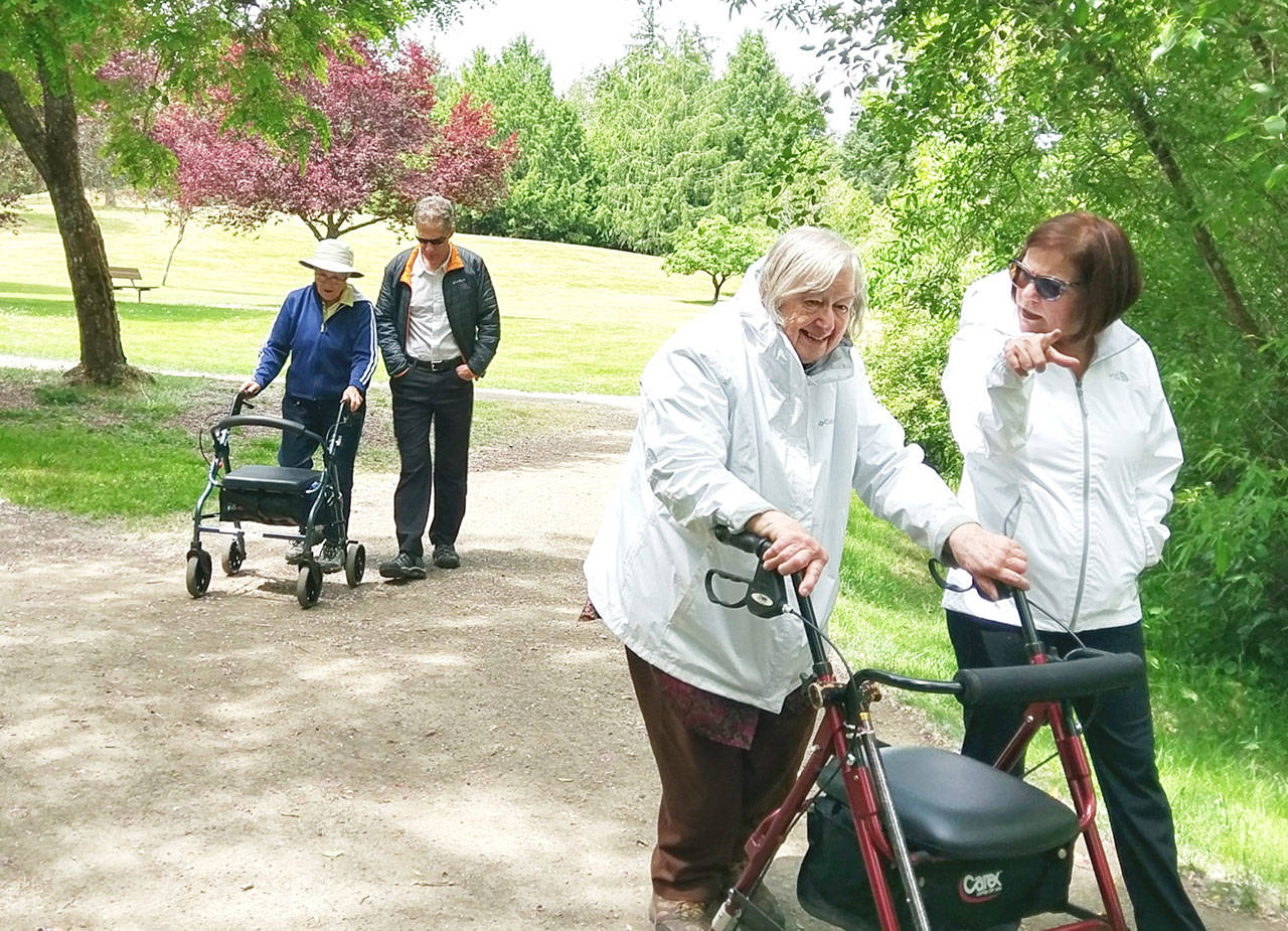 IVC volunteer Jeff Brown walks with Theresa Obrien as fellow IVC volunteer Elizabeth Ristine assists Janet Wick during an outing at Battle Point Park. (Photo courtesy of IVC)