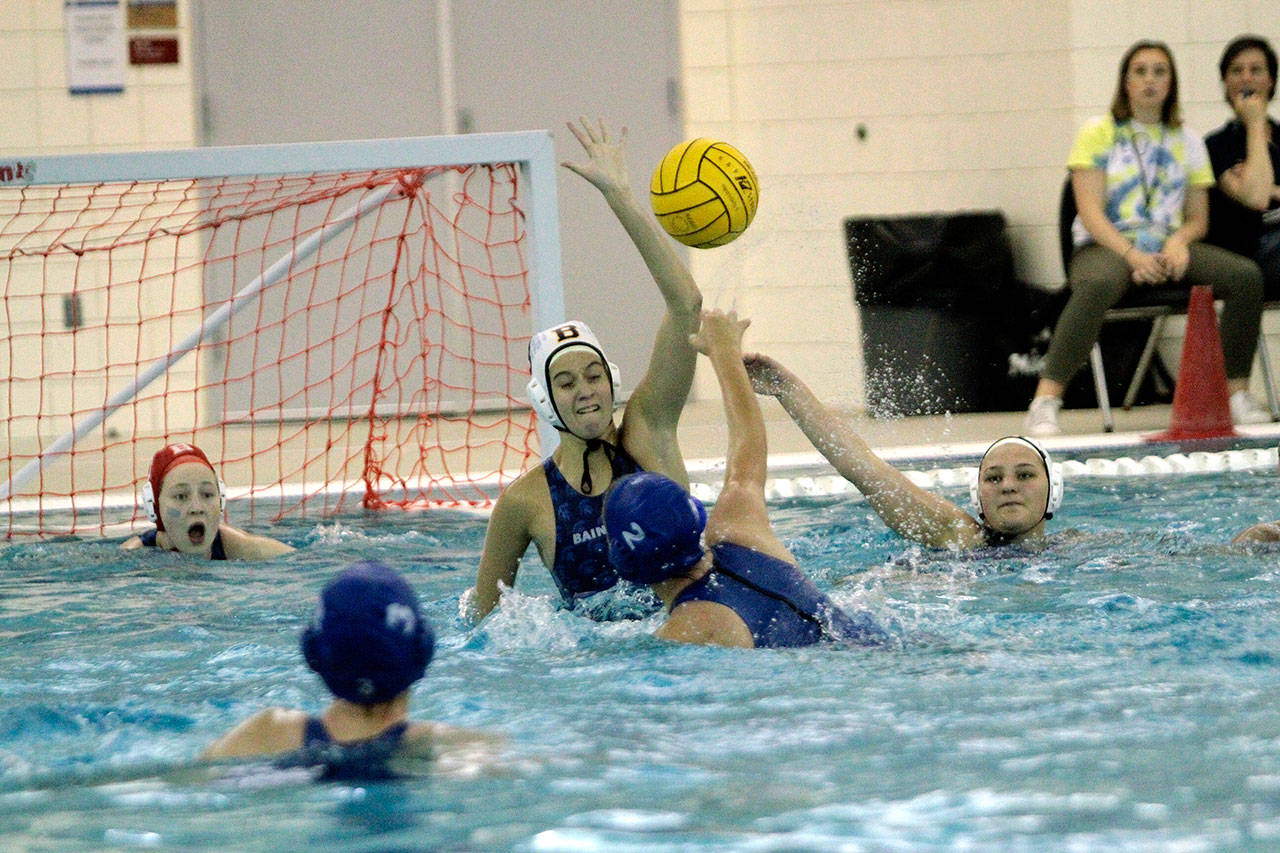 Kristina DuPont rises to block a shot from Ingraham while teammate Grace Carson (right) watches. (Brian Kelly | Bainbridge Island Review)