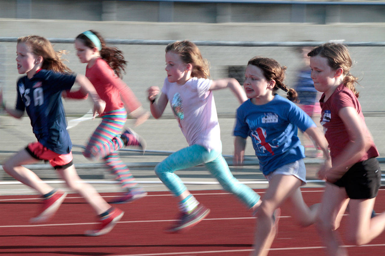 Luciano Marano | Bainbridge Island Review - A slew of speedy young girls spring from the starting line during an early round of sprints at the year’s first Kiwanis All-Comers Track Meet at Bainbridge High School Monday.