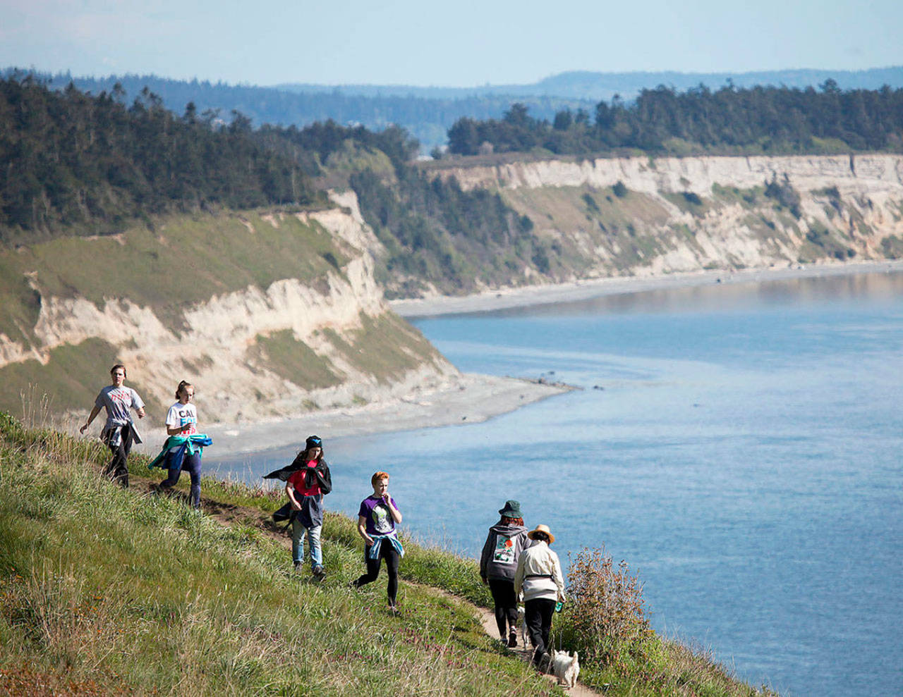 Hikers make their way along the Bluff Trail at Ebey’s Landing near Coupeville on Whidbey Island. At its highest point, the bluff sits about 260 feet above sea level, providing stunning views of the Strait of Juan de Fuca and Olympic Mountains. (Ian Terry | Herald file)