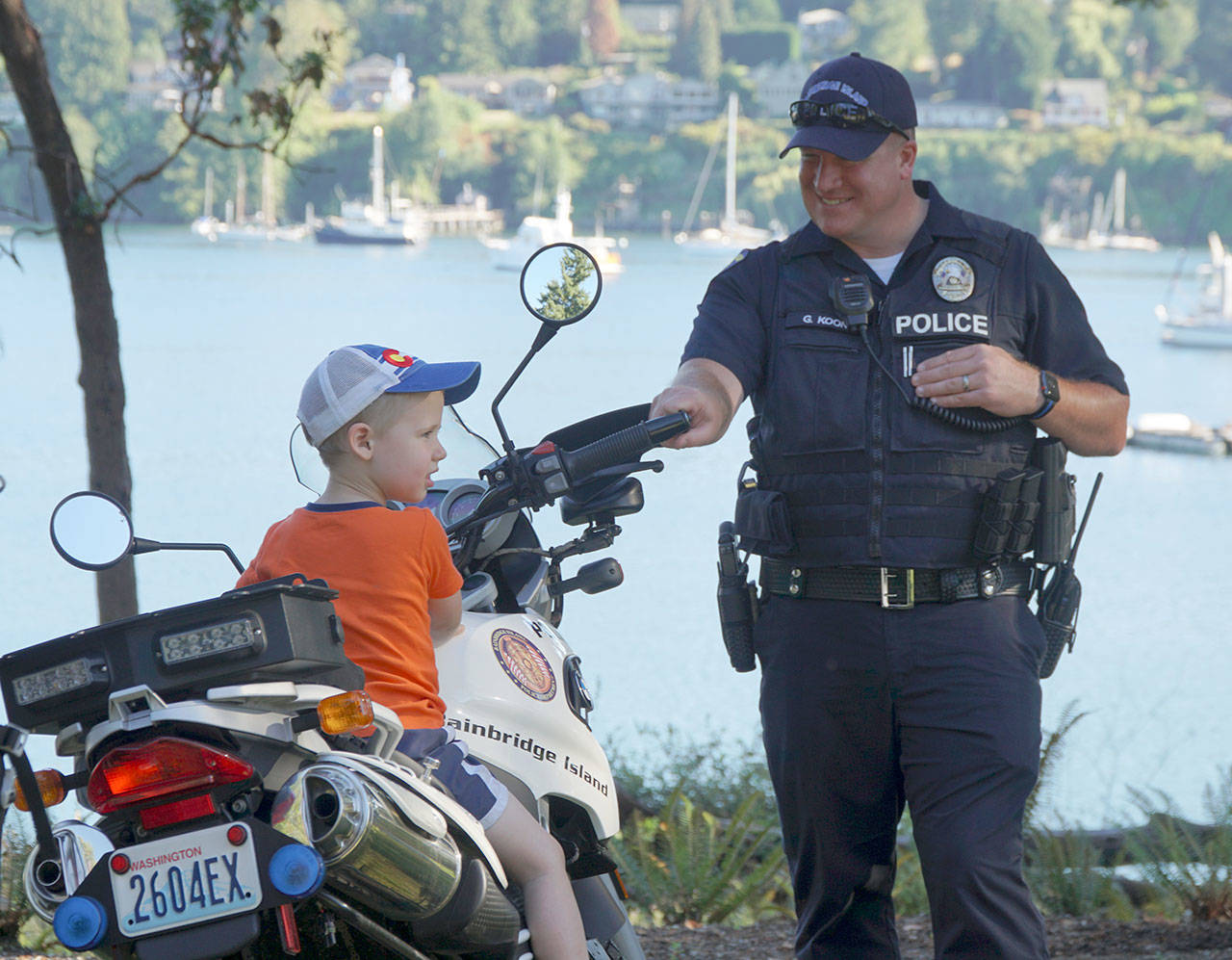 Luciano Marano | Bainbridge Island Review - Bainbridge Island Police Department Officer Gary Koon gives a young attendee a chance to sit on his bike during last year’s National Night Out event in Waterfront Park.