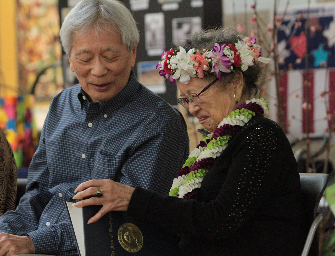 Kay Sakai Nokao admires a proclamation presented to her by Gov. Jay Inslee at her 100th birthday celebration as her son Bill Nakao looks on. (Brian Kelly | Bainbridge Island Review)