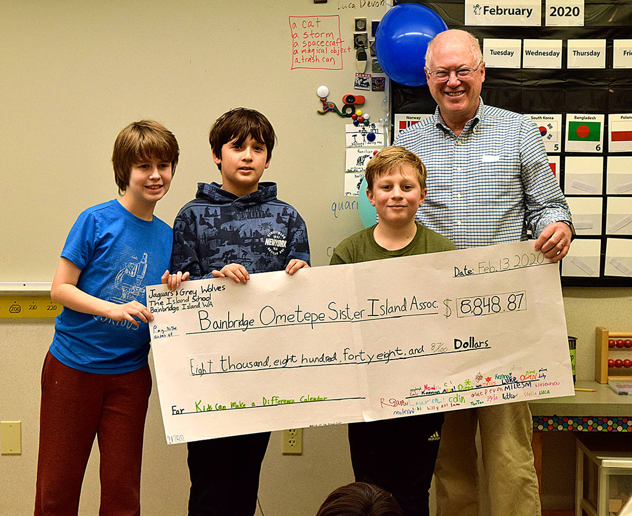 Three fifth-grade students present a check from their calendar sales to Paul Carroll of Bainbridge Ometepe Sister Islands Association. (Photo courtesy of The Island Schoo)
