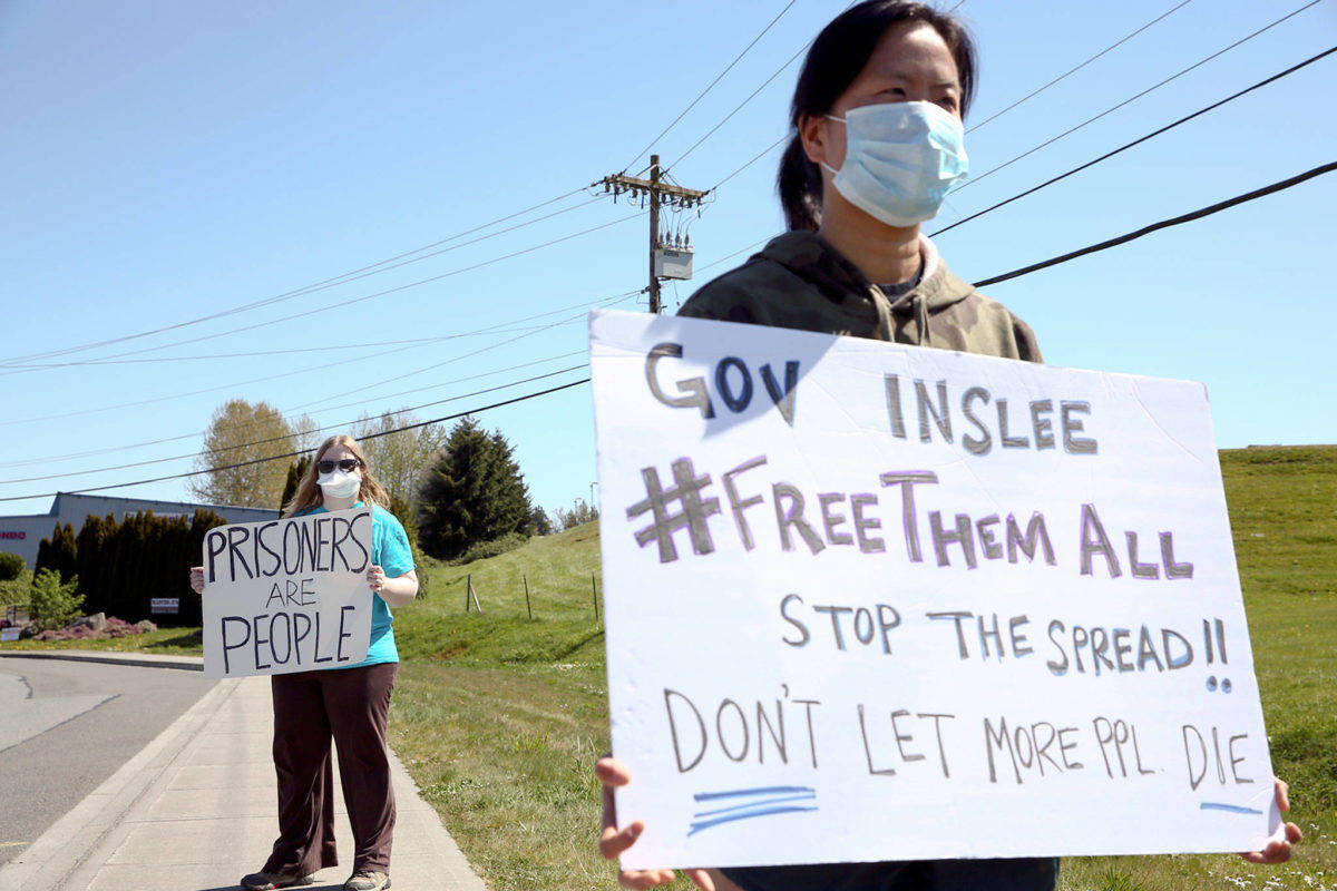 Masked protestors stand outside the grounds of the Monroe Correctional Complex in Monroe on Thursday. (Kevin Clark | The Herald)