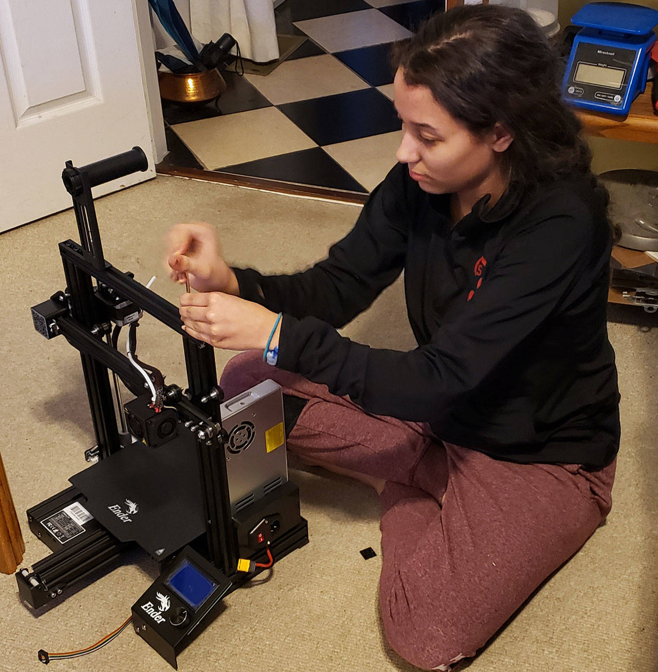 Spartronics leadership team member Merrill Keating uses a 3D printer she assembled during Spring Break to print ear protectors for masks being made for health care professionals and first responders. (Photo courtesy of Enrique Chee)