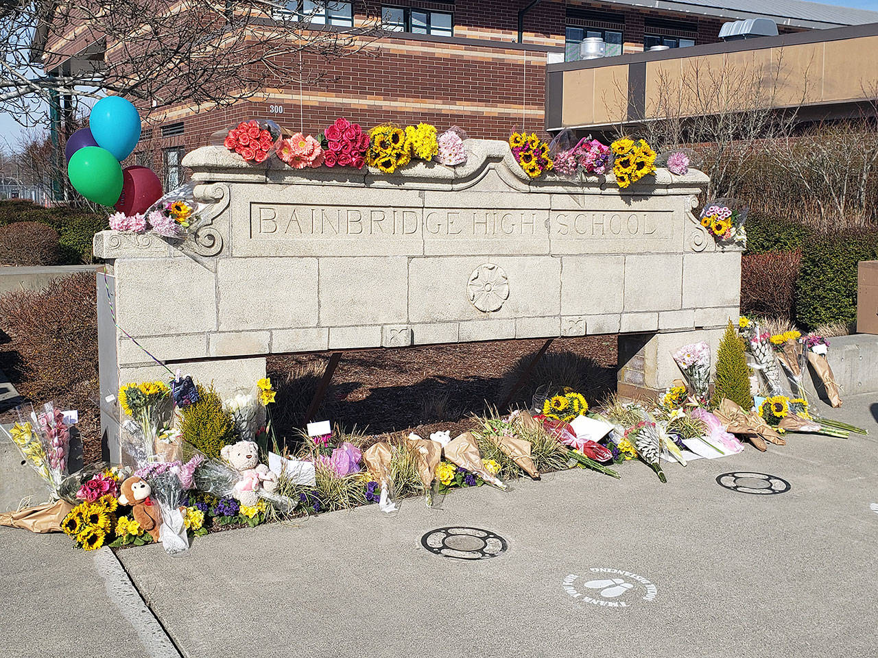 Flowers and other items were placed at the front of Bainbridge High School Wednesday to honor the three students who were killed in a single-vehicle rollover Tuesday. Tyler Shuey/Bainbridge Island Review