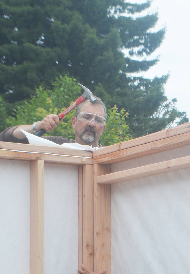 A volunteer hammers two sides of the tiny house together.