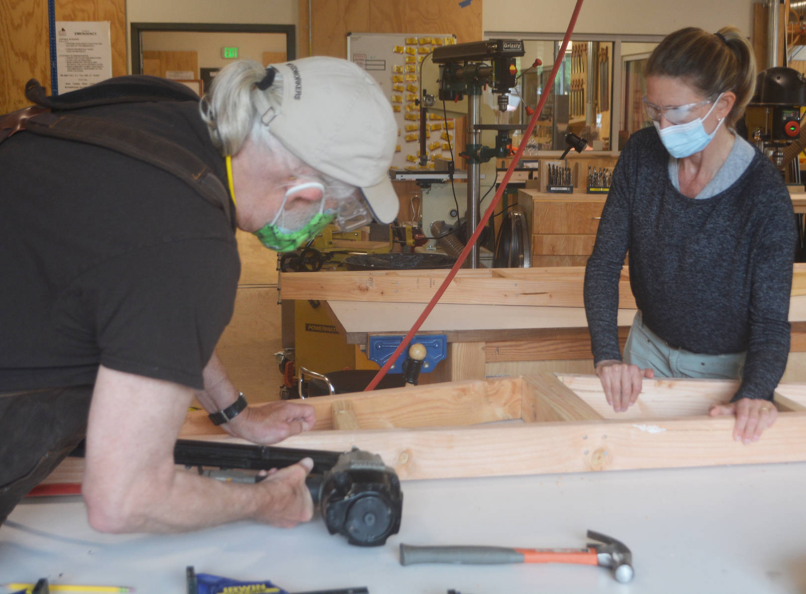 "Stretch" uses a nail gun as he puts together one of the rafters, while Tammy Galbraith observes.