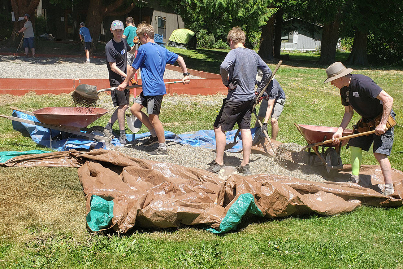 A group of church members digs up gravel into wheelbarrows.