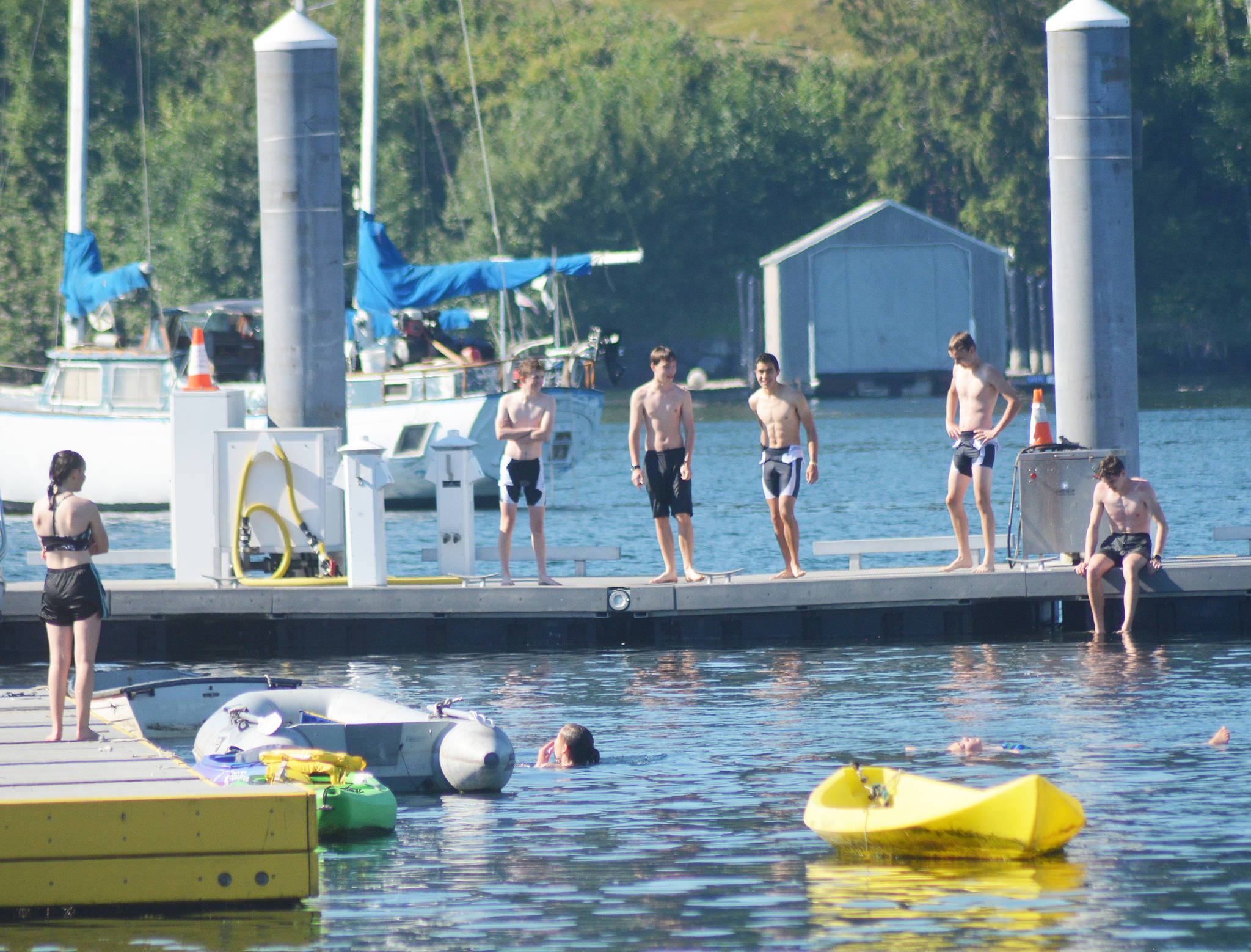 Young adults go swimming off a dock in Eagle Harbor Monday morning.