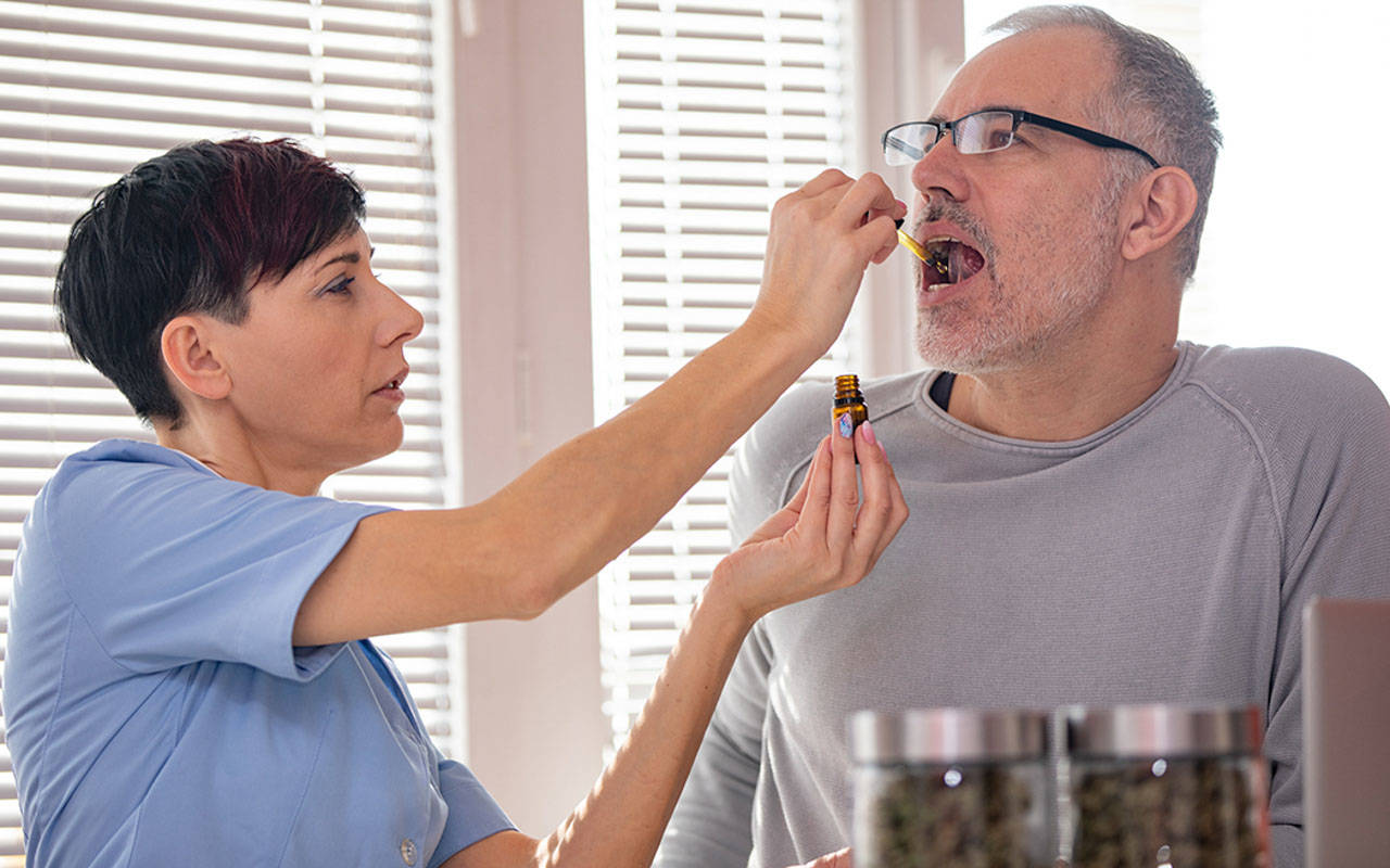 Alternative Healthcare Worker Dropping CBD Oil on Patient's Tongue.