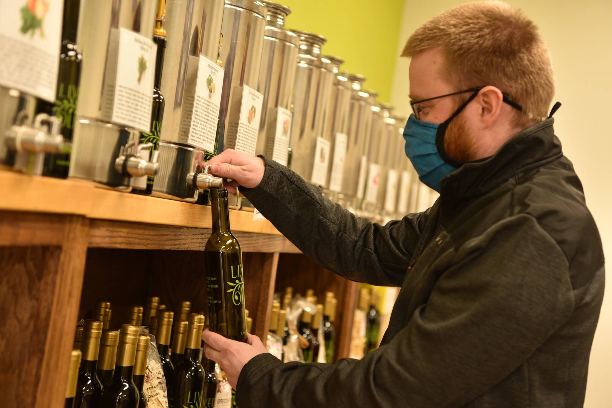 Jeremy Wake, co-owner of Lively Olive Tasting Bar, fills a bottle with olive oil.