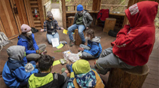 In a fort-like setting, students learn about the environment at IslandWood. Courtesy Photo