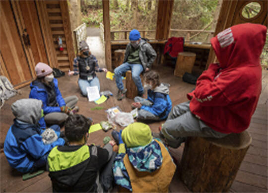In a fort-like setting, students learn about the environment at IslandWood. Courtesy Photo