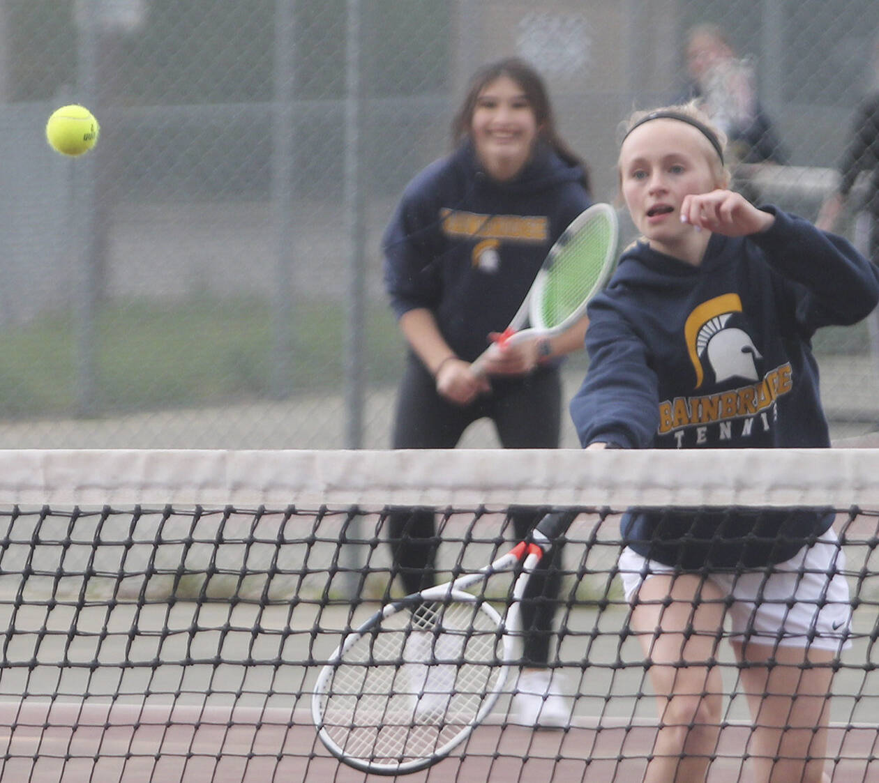 Aya Gatto, in background, smiles as BHS teammate Kristine Walker puts away a backhand volley at the net.