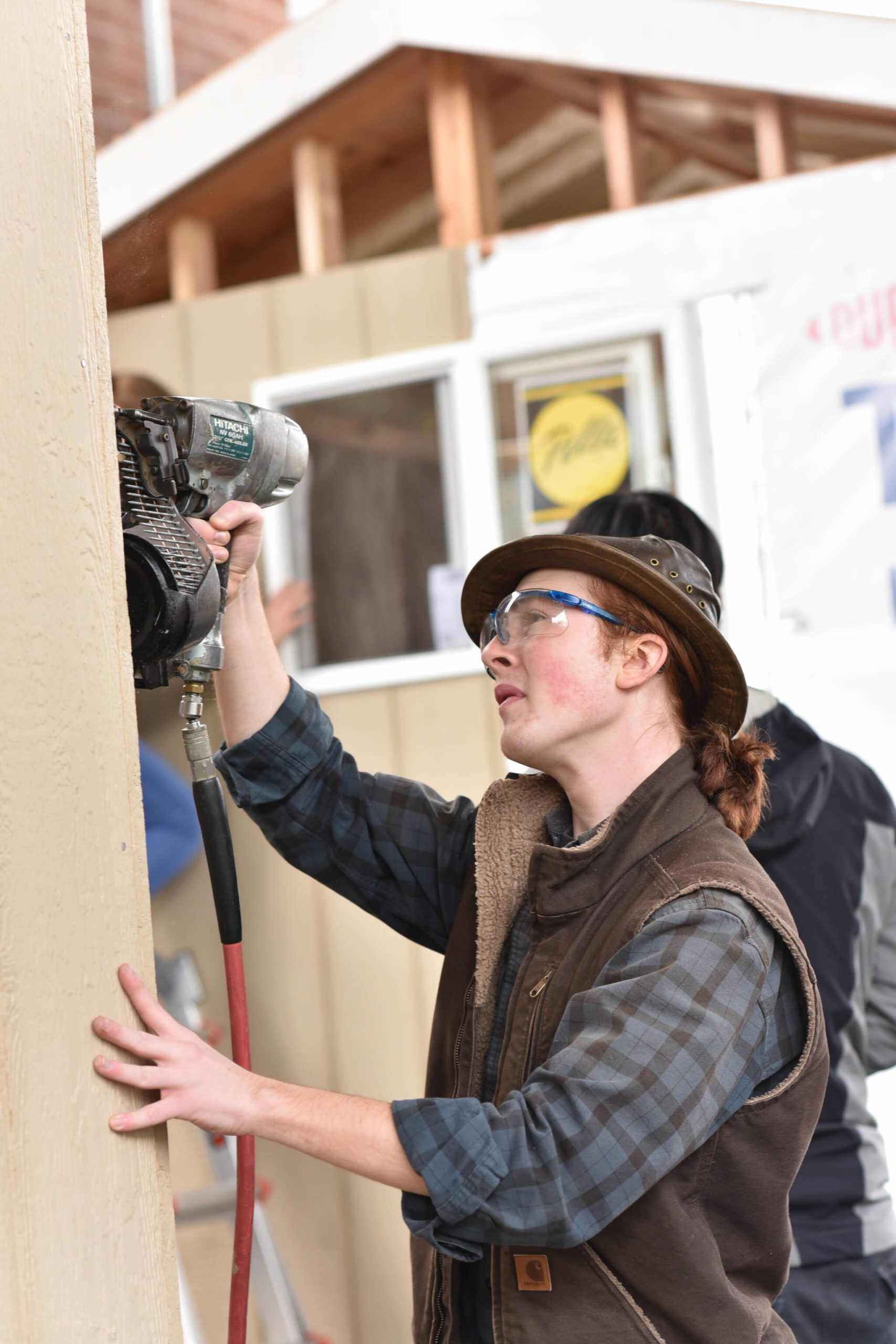 Senior Alexander McAbee nails up siding to one of the tiny houses.