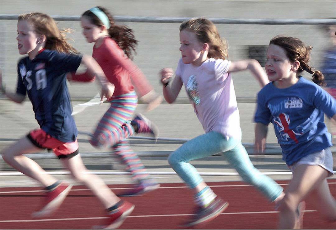 A group of girls runs down the track at a previous all-comer's meet.