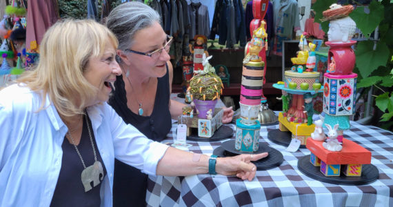 Mixed media artist Dana Watson shows one of her whimsical assemblage pieces to a tour visitor. Courtesy Photos.