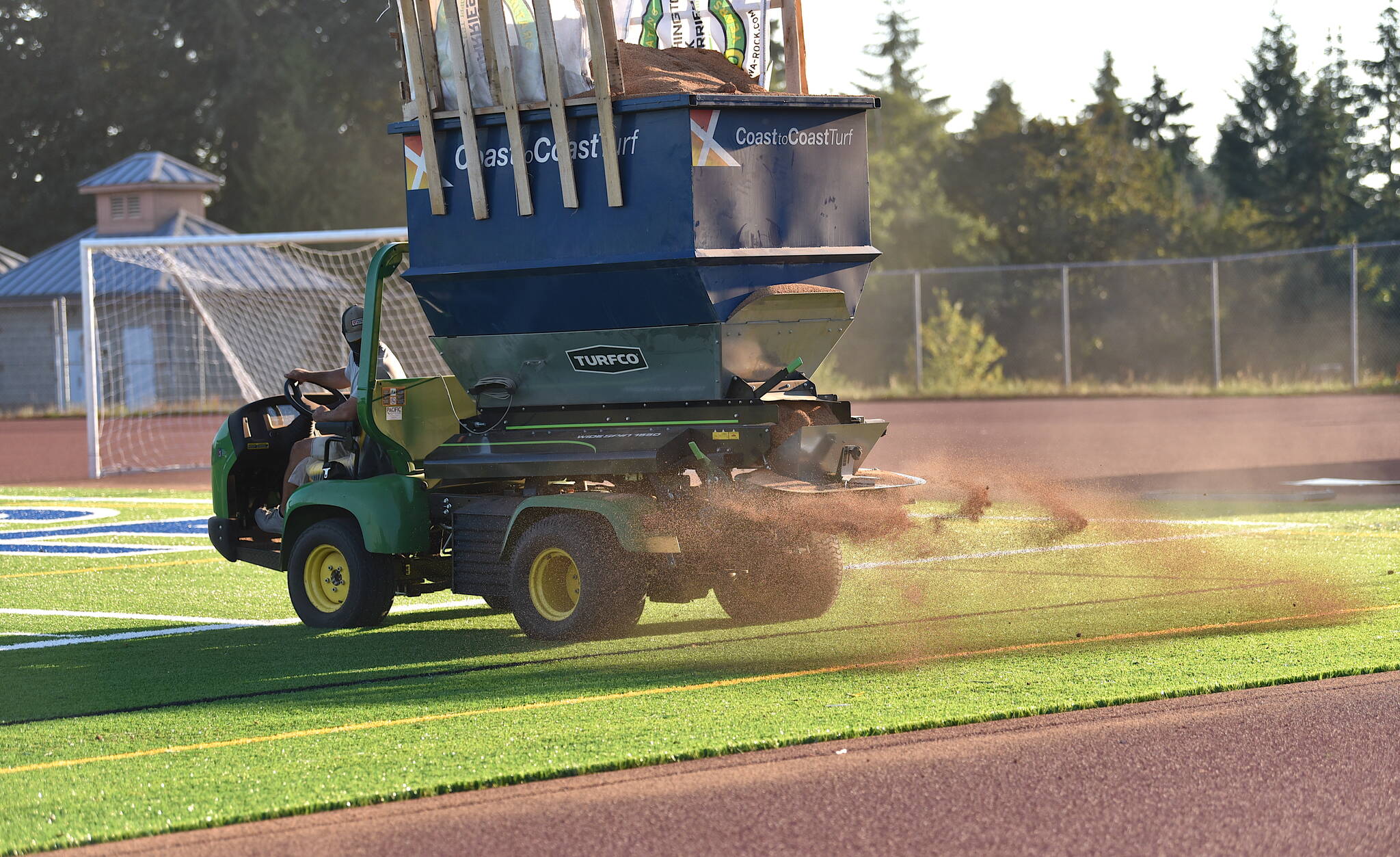 Chip Walker drives a spreader that applies infill to the new turf installed at BHS Memorial Field.