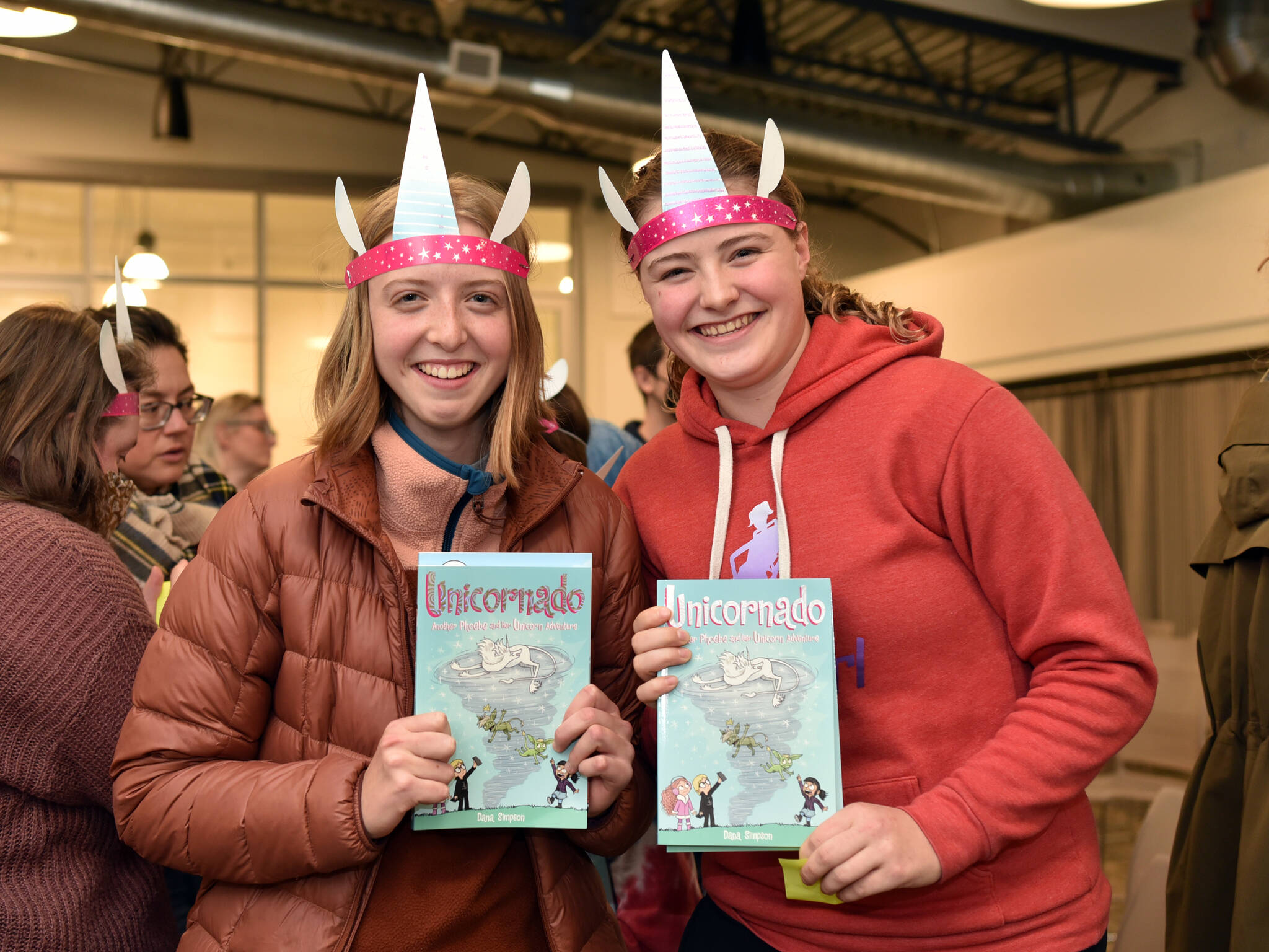 Bea Skipton and Allie Poulson-Houser pose with their Phoebe and her Unicorn books during a book signing event with author Dana Simpson.