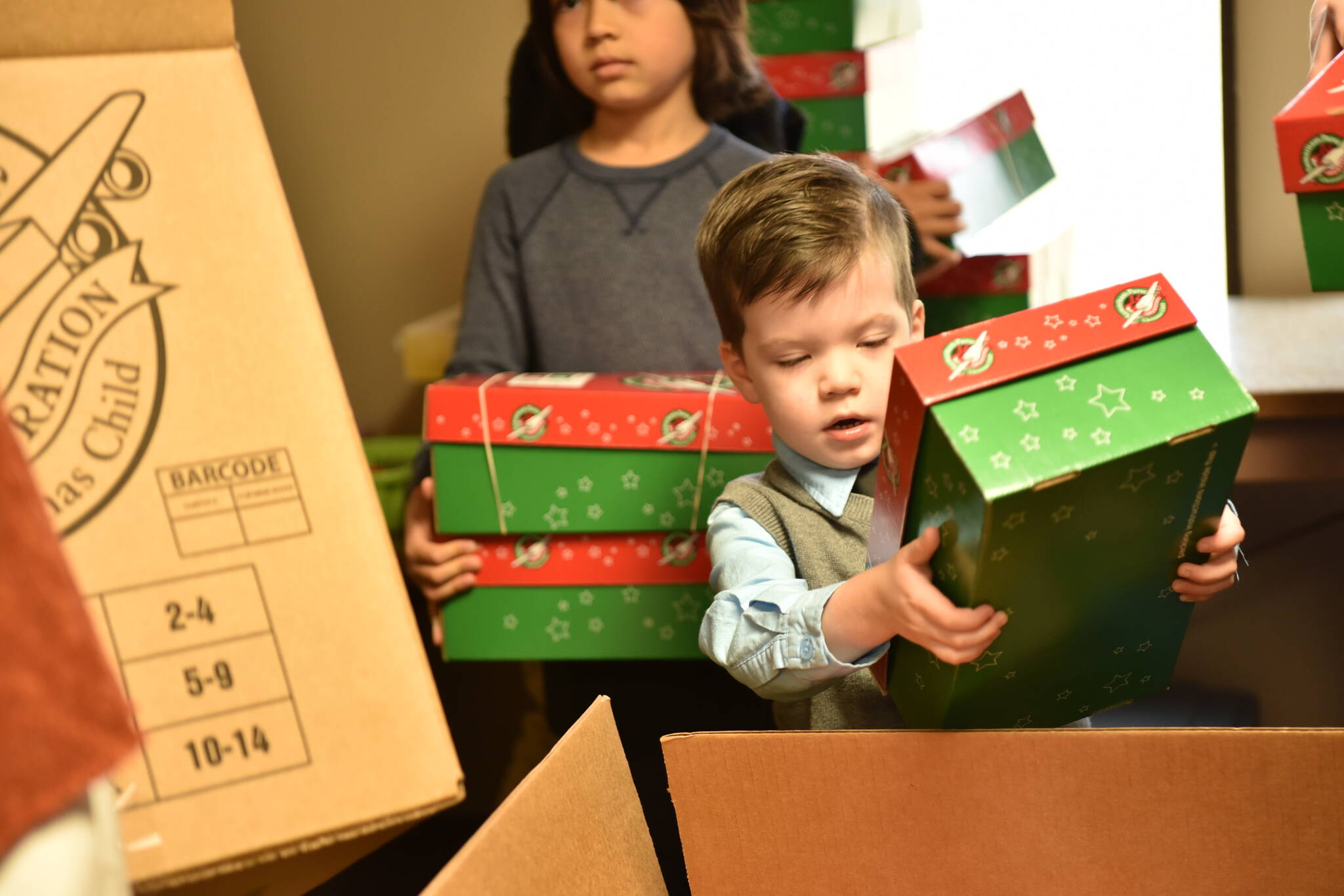 Luke Garrard, 3, puts a shoebox into the shipping box.