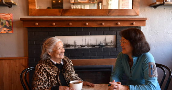 Frances Kitamoto Ikegami and Carol Reitz sit for tea in front of the fireplace where Japanese Islanders were forced to register for exclusion in 1942. Nancy Treder/Kitsap News Group