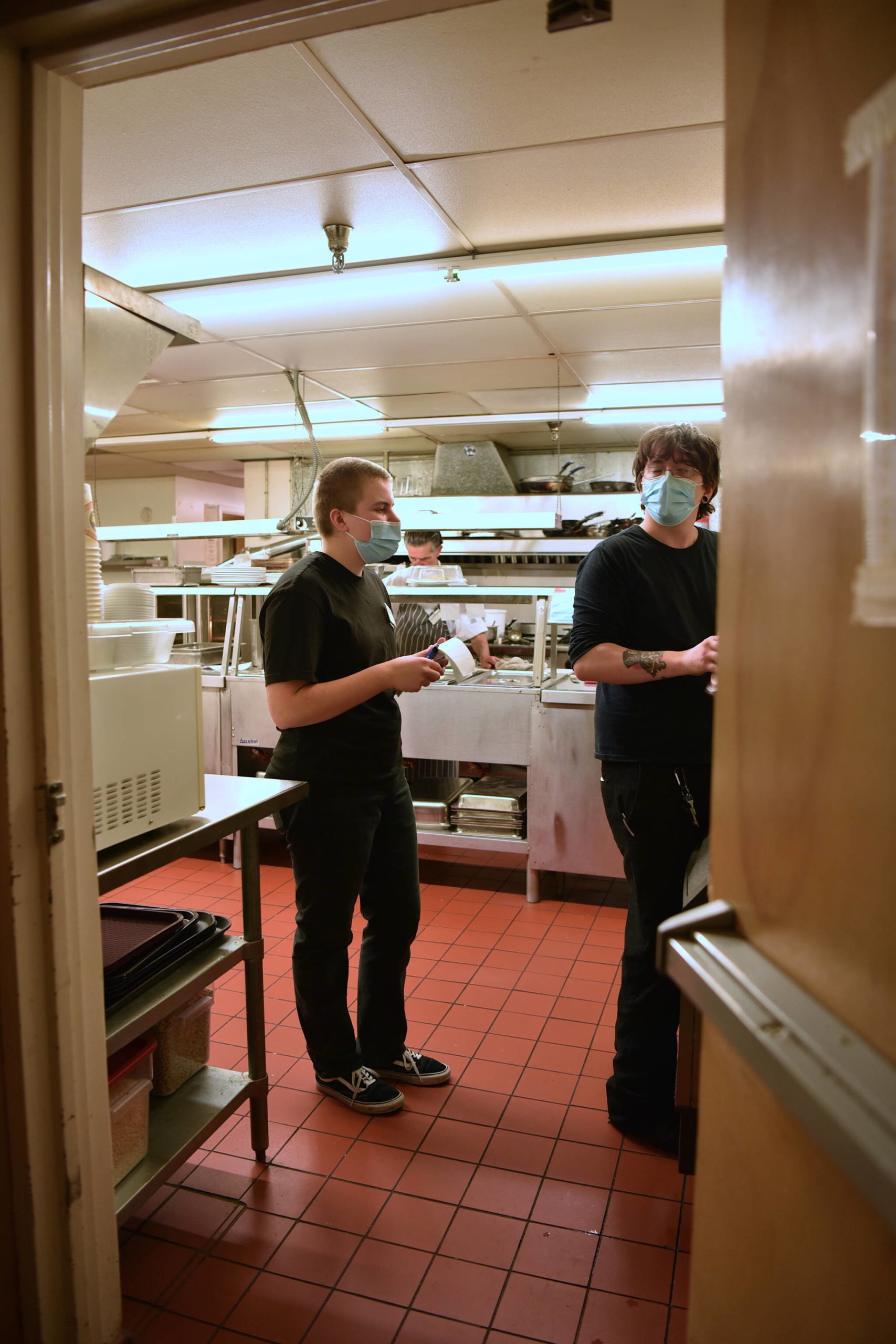 Maggie Rohrbach speaks with a co-worker in the kitchen at the Madison House dining room.