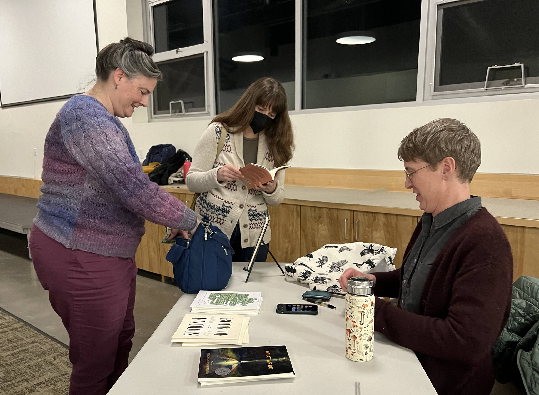 Kathryn Smith, the January 2023 Bloedel Reserve creative resident, autographs one of her poetry books for Amanda Williamsen, who read a poem about cats at the BARN Open Mic night Jan. 19.