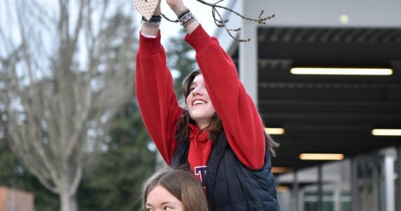 Bainbridge High School seniors Lauren Feeney and Lily Freeman help each other decorate trees with ceramic hearts Feb. 13. BHS senior and ceramic club president Thomas Robinson said they want to 'Share the Love' with students and faculty. The club created 565 ceramic valentines to hang on the trees. Also, students chose specific high school staff to honor and wrote them cards of kindness. Nancy Treder/Kitsap News Group Photos