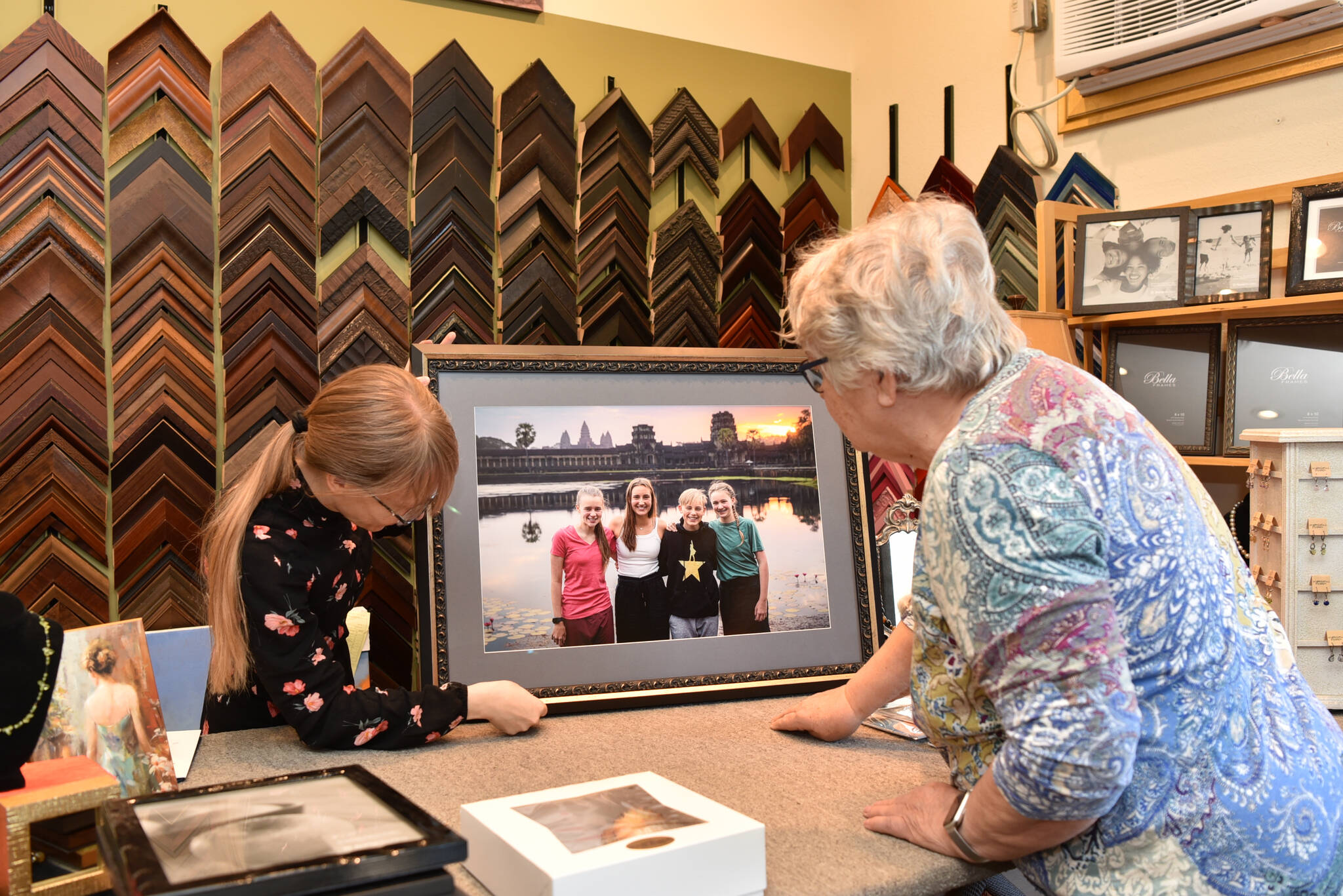 Cheryl Jaszewski examines a framed photo that Crista Dougherty prepared for her. It is one of more than 30 pieces that Julie's Frame Gallery has created for her.