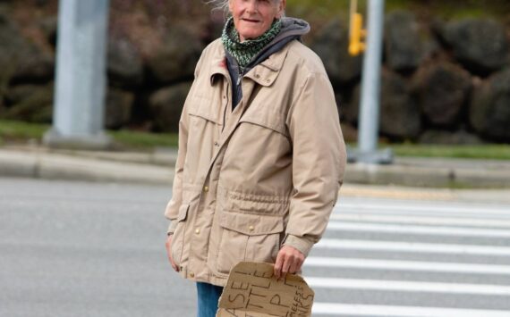 A man stands on the curb nearby Bremerton’s Fred Meyer asking for cash from passing cars. Elisha Meyer/Kitsap News Group