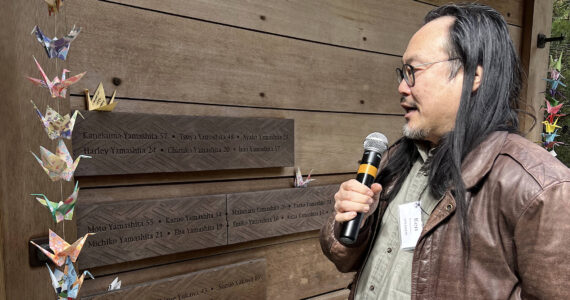 Ken Matsudaira, director of Community and Cultural Programs at the Bainbridge Island Art Museum, reads the last of the 276 names on the memorial wall. Nancy Treder/Kitsap News Group Photos