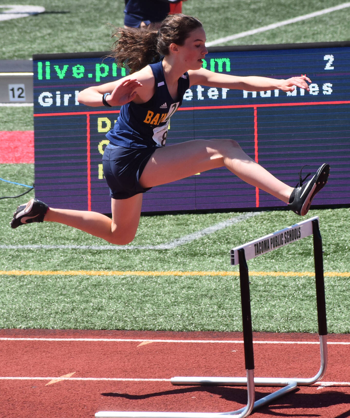 Bainbridge Sabine Hartenstine jumps over the hurdle during her race.