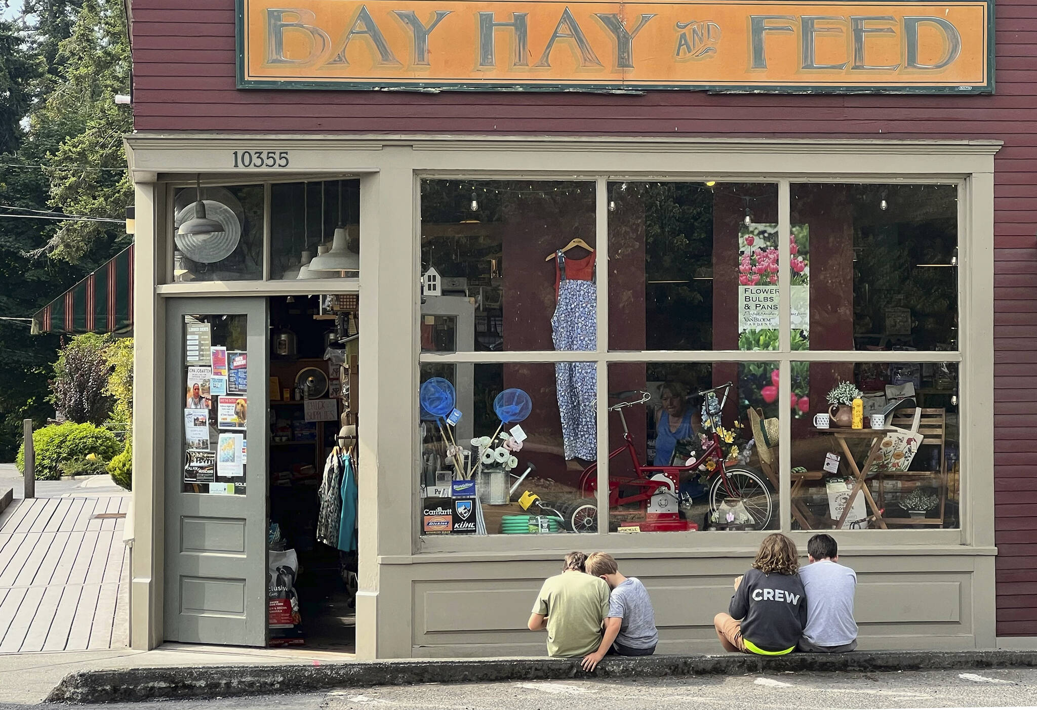 This courtesy photo taken by Rob Swan of the Bay Hay and Feed store in Rolling Bay looks like a Norman Rockwell image or something that could have come out of the 1950s as friends sit on a curb next to the Bainbridge Island store.