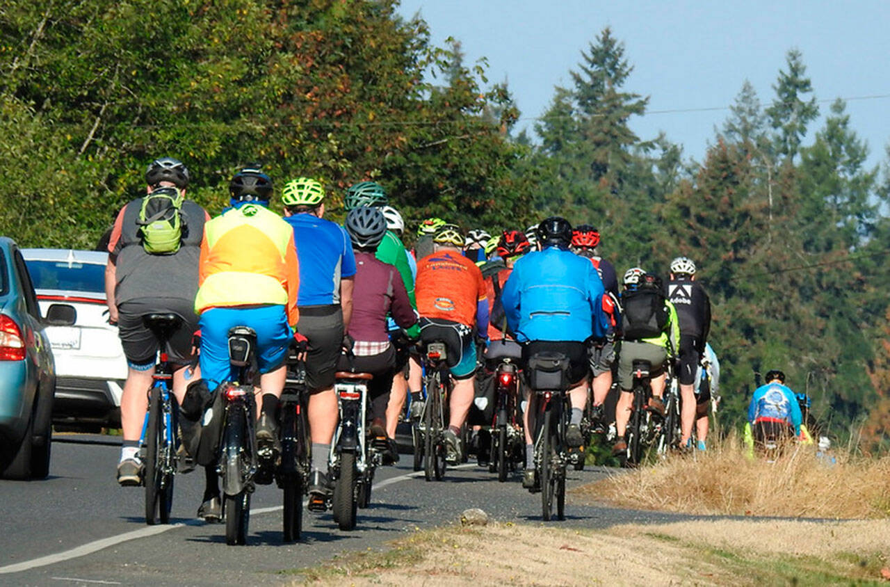 Vehicles pass a group of cyclists.