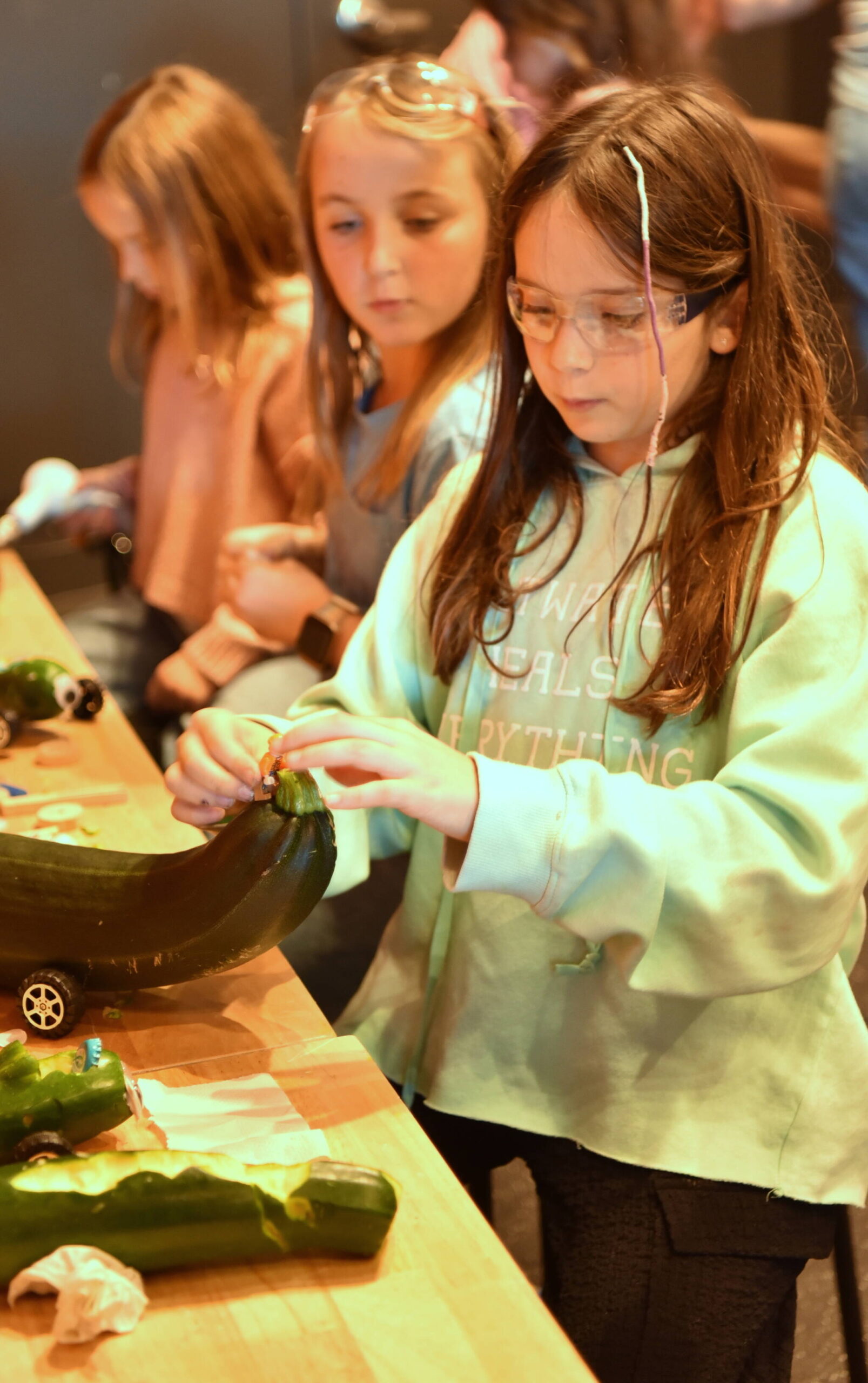 Blakely Elementary student Sage Dikman works on her zucchini car as Hanna-Lisa Barlak looks on.
