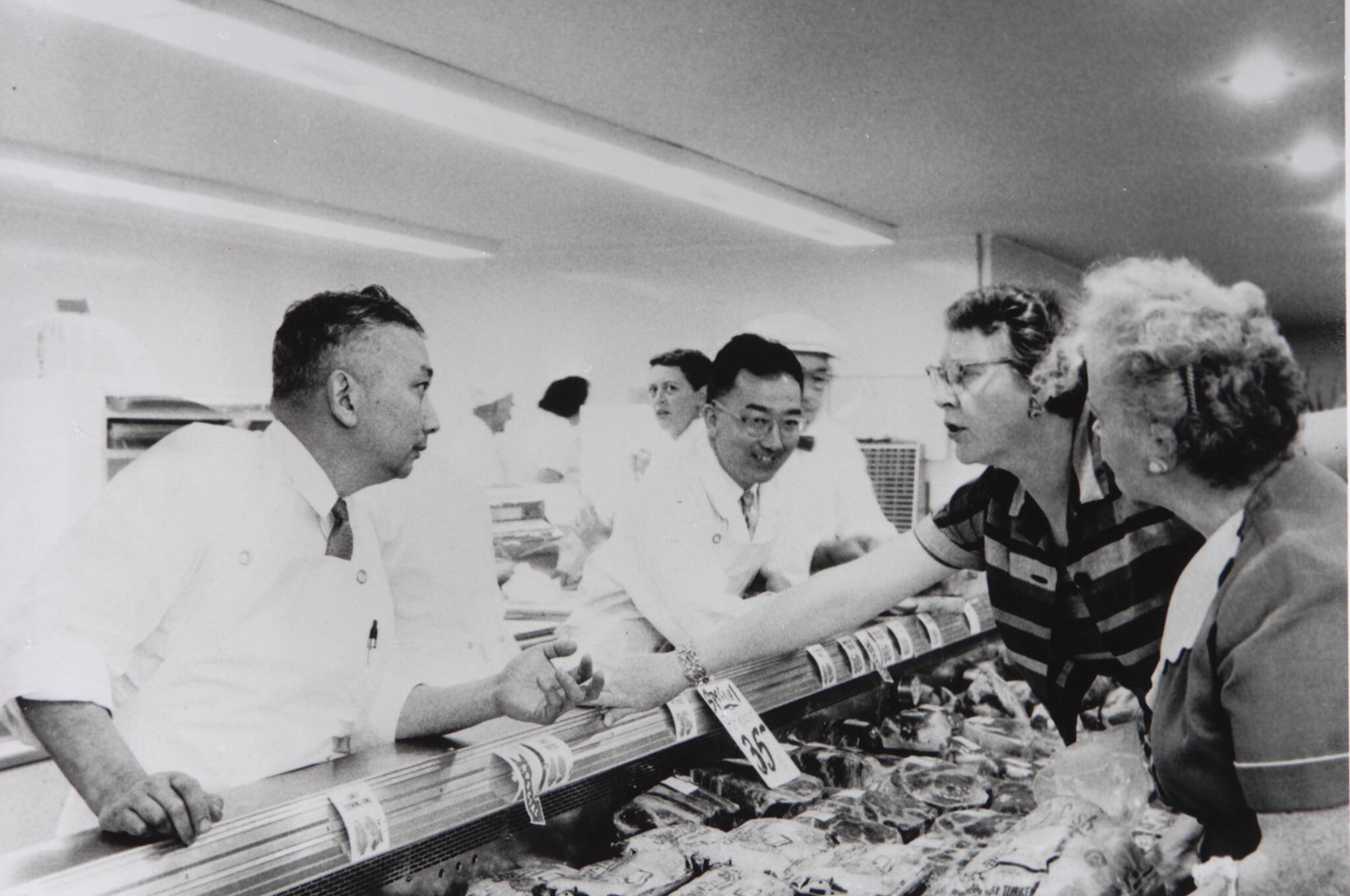 T&C courtesy photo
Brothers Mo and John Nakata speak with customers at the Town & Country Market butcher counter in an undated photo.