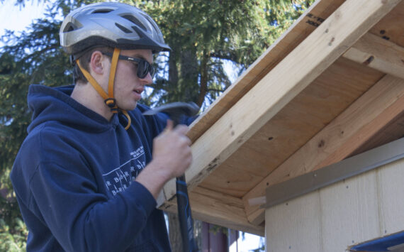 Student James Phillips secures a piece of plywood to the roof of the Hyla students’ tiny home project.