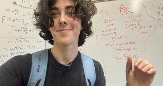 Ella McRitchie courtesy photos
McRitchie smiles and gestures toward her calculations, displaying stitches on her thumb from a pole-vaulting accident.